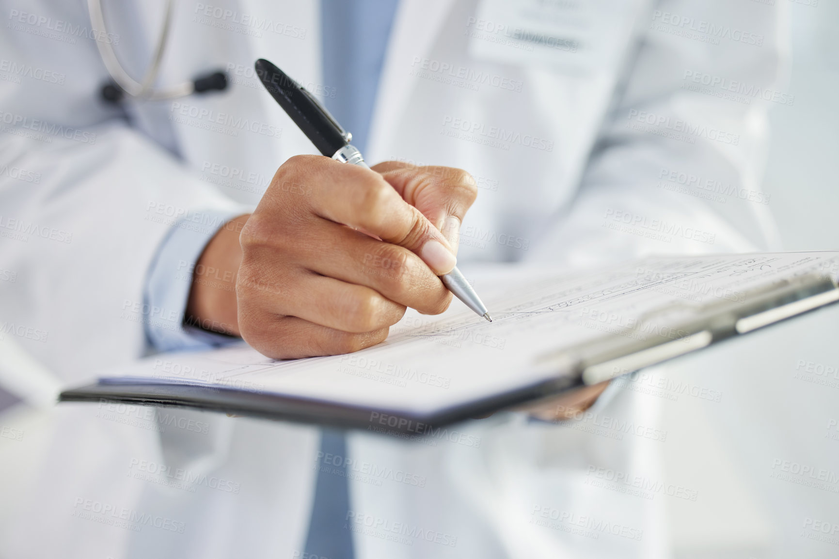 Buy stock photo Cropped shot of an unrecognizable doctor standing alone and writing on her clipboard in her clinic