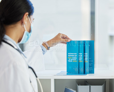 Buy stock photo Shot of an unrecognizable doctor standing alone in her clinic and organising her leaflets