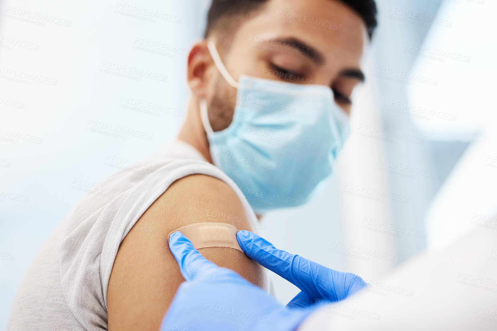 Buy stock photo Shot of an unrecognizable doctor putting a band-aid on her patient after giving him the Covid vaccine
