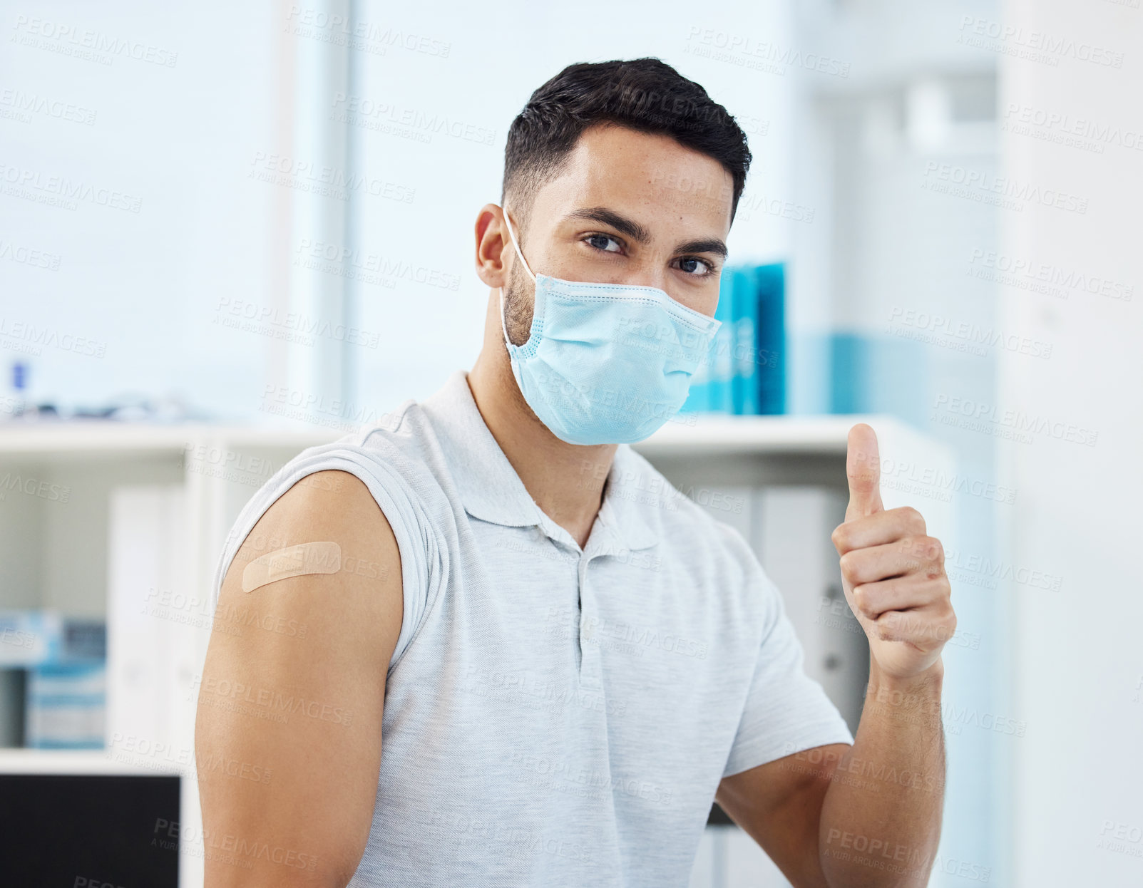 Buy stock photo Shot of a young man wearing a face mask and showing a thumbs up after getting his Covid vaccine