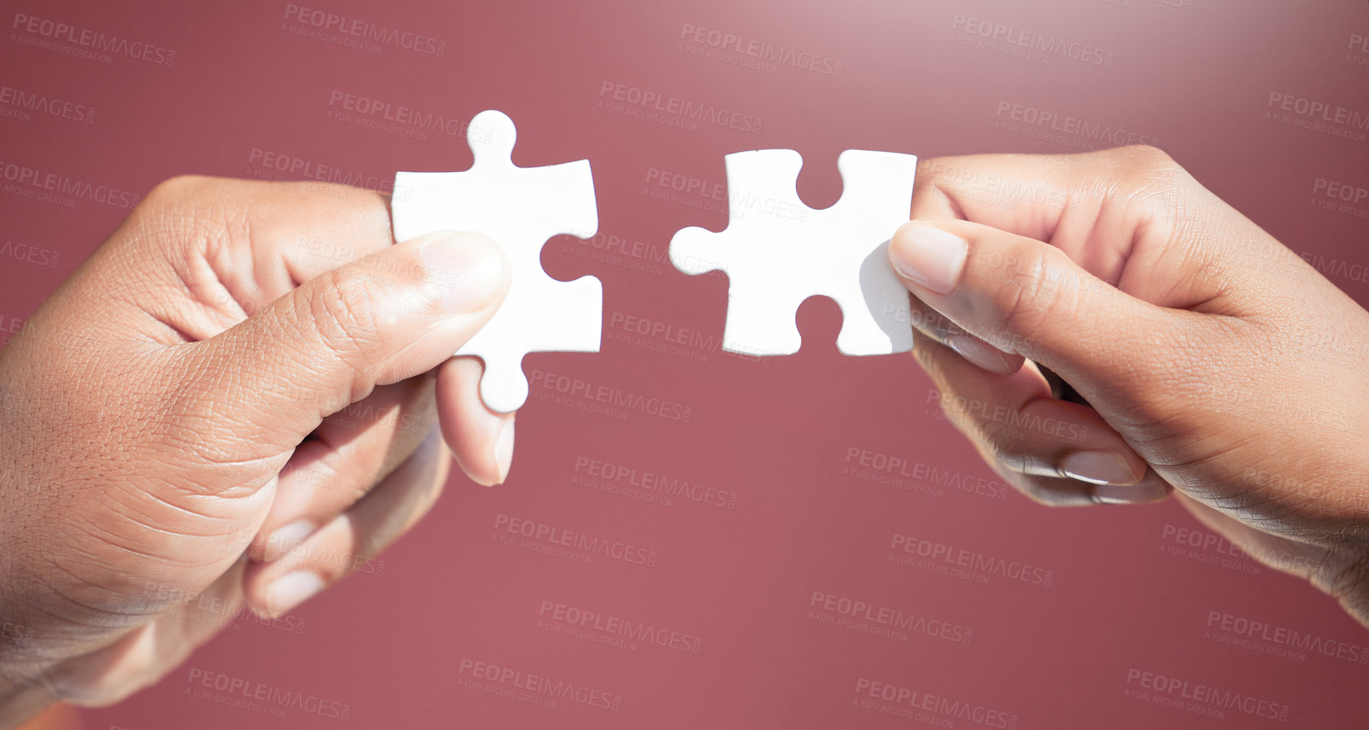 Buy stock photo Cropped shot of two unrecognizable businesspeople fitting puzzle pieces together in studio against a red background