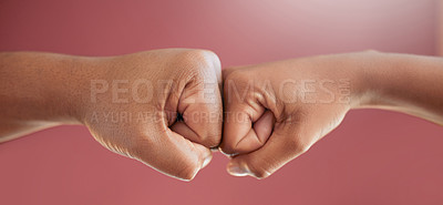 Buy stock photo Cropped shot of two unrecognizable people fist bumping in studio against a red background