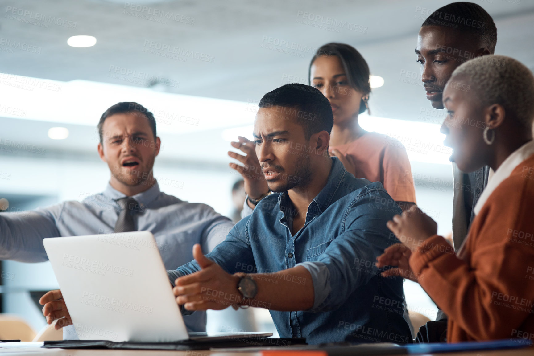 Buy stock photo Shot of a young businessman breaking a laptop during a team meeting in a modern office