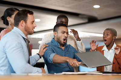 Buy stock photo Shot of a young businessman breaking a laptop during a team meeting in a modern office