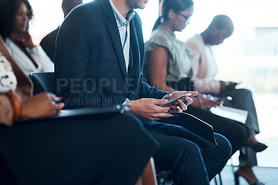 Buy stock photo Shot of a group of young businesspeople using cellphones during a a meeting in a modern office