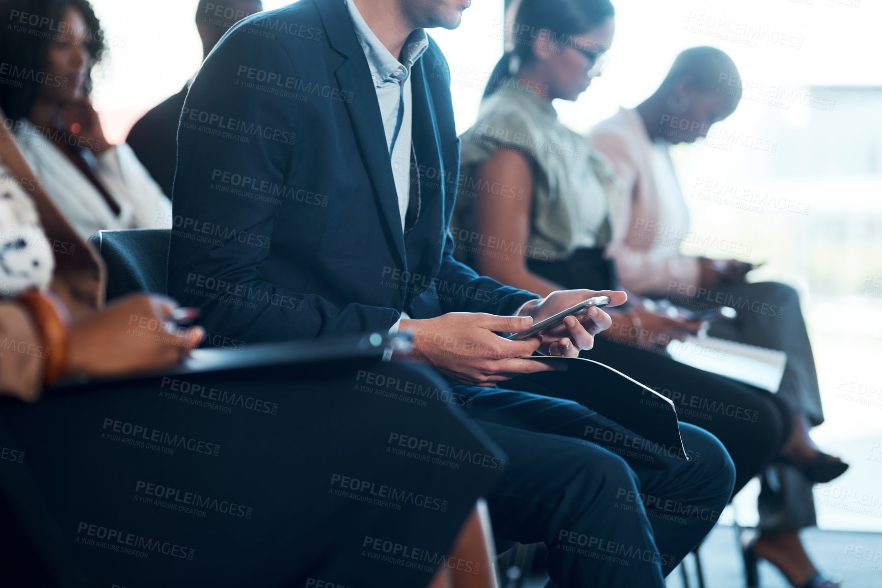 Buy stock photo Shot of a group of young businesspeople using cellphones during a a meeting in a modern office