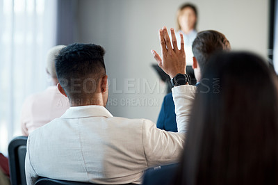 Buy stock photo Rearview shot of a young businessman raising his hand during a conference in a modern office