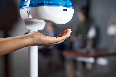 Buy stock photo Shot of a businesswoman using a hand sanitising dispenser in a modern office