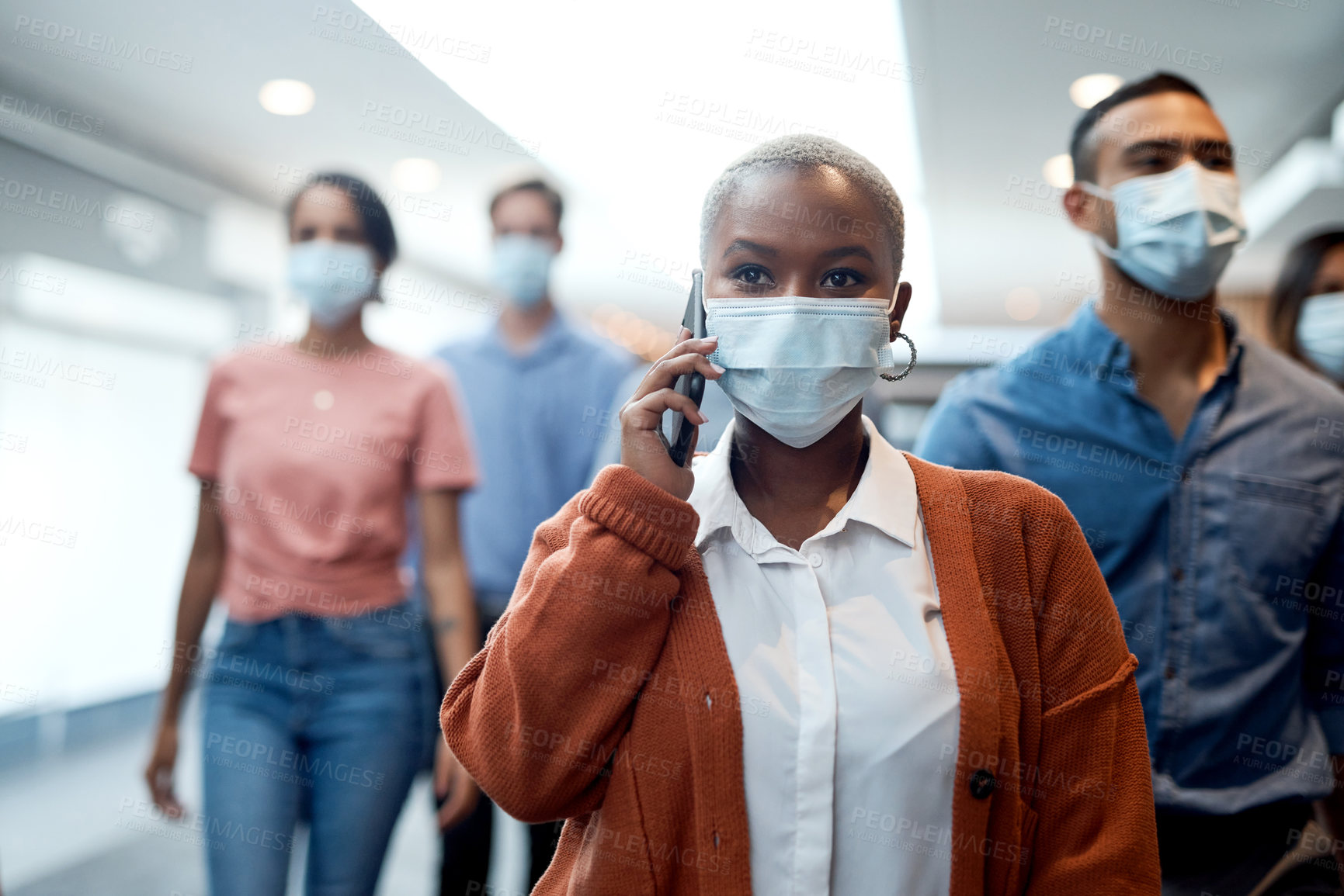 Buy stock photo Shot of a masked young businesswoman using a smartphone during a conference