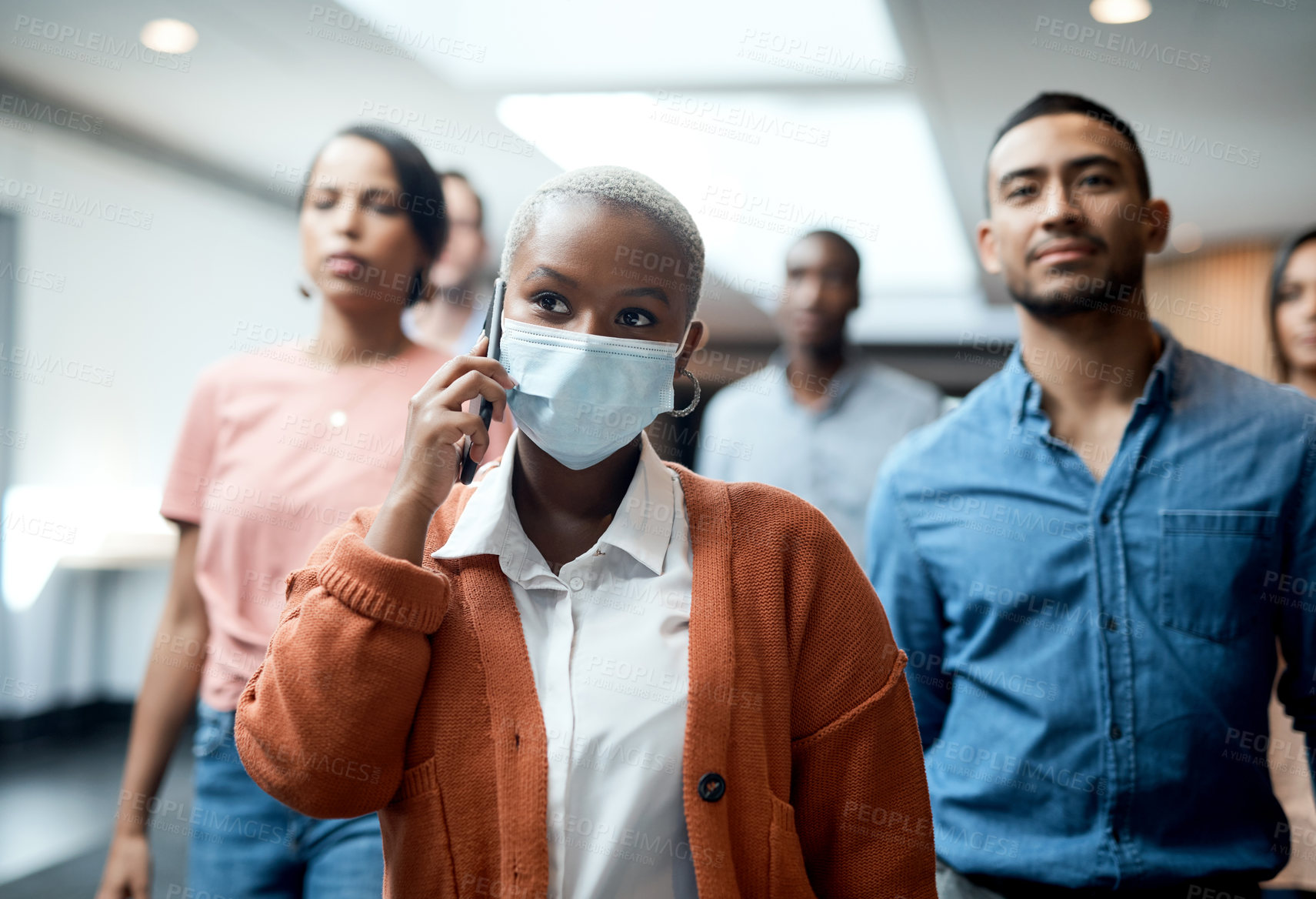 Buy stock photo Shot of a masked young businesswoman using a smartphone during a conference