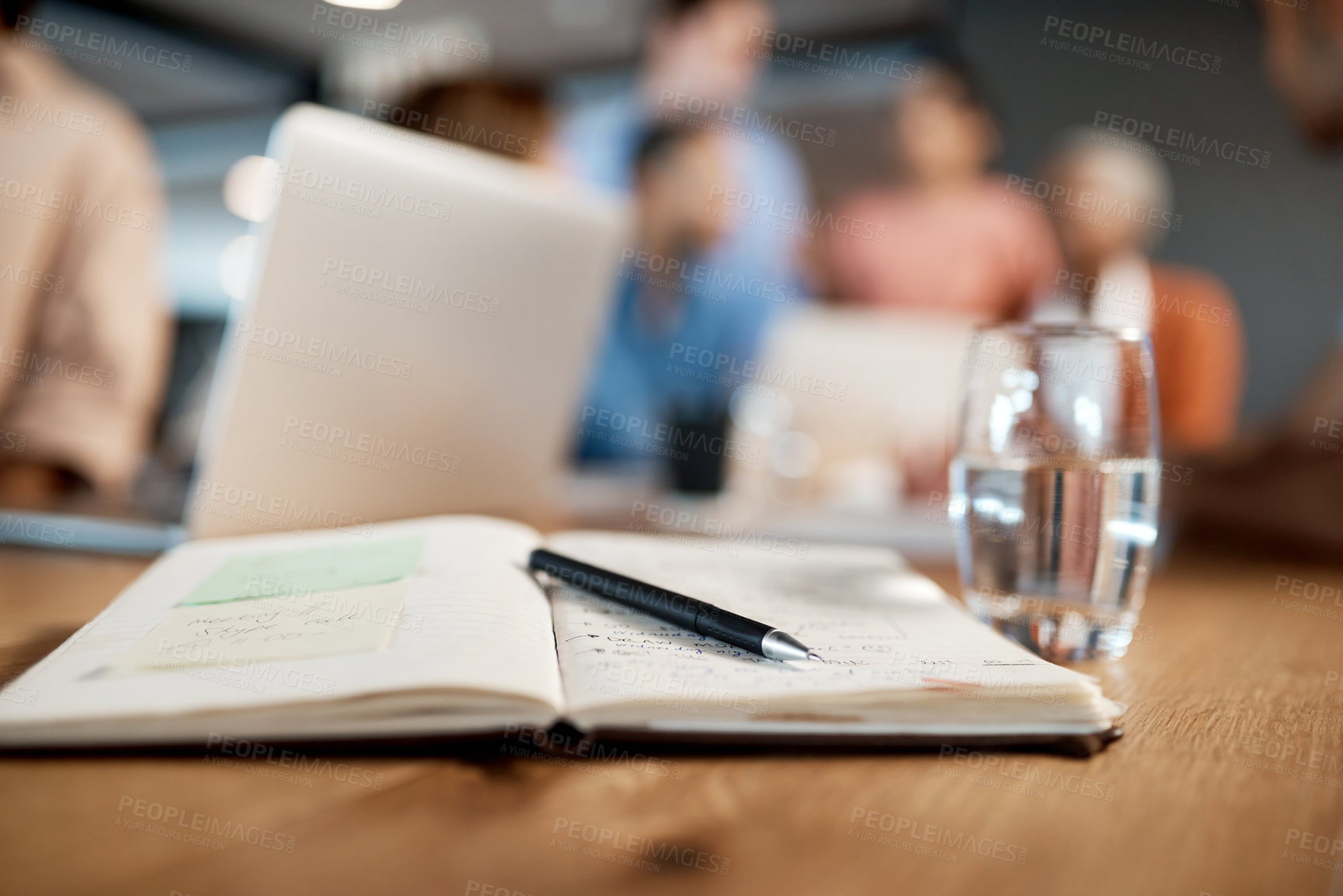 Buy stock photo Shot of a notebook, pen and glass of water in a table at a conference