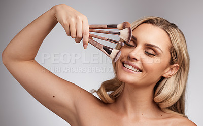 Buy stock photo Studio portrait of a beautiful young woman holding a set of makeup brushes against a grey background