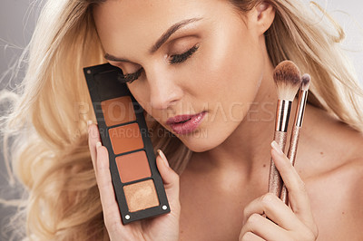 Buy stock photo Studio portrait of a beautiful young woman holding a set of makeup brushes against a grey background