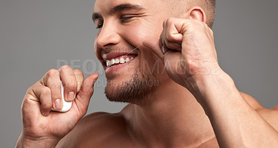 Buy stock photo Studio shot of a handsome young man flossing his teeth against a grey background