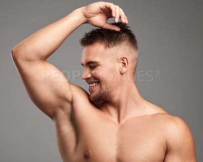 Buy stock photo Studio shot of a handsome young man smelling his armpit against a grey background