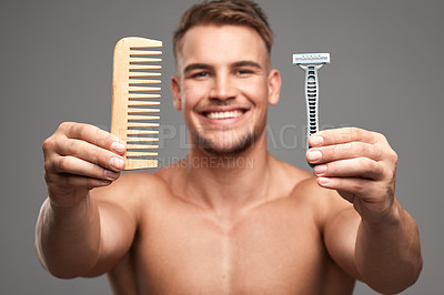 Buy stock photo Studio shot of a handsome young man holding a comb and shaving brush against a grey background