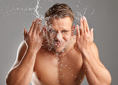 Buy stock photo Studio shot of a handsome young man washing his face against a grey background