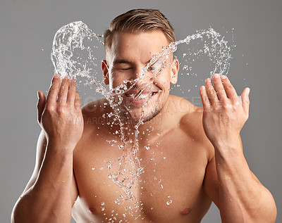 Buy stock photo Studio shot of a handsome young man washing his face against a grey background