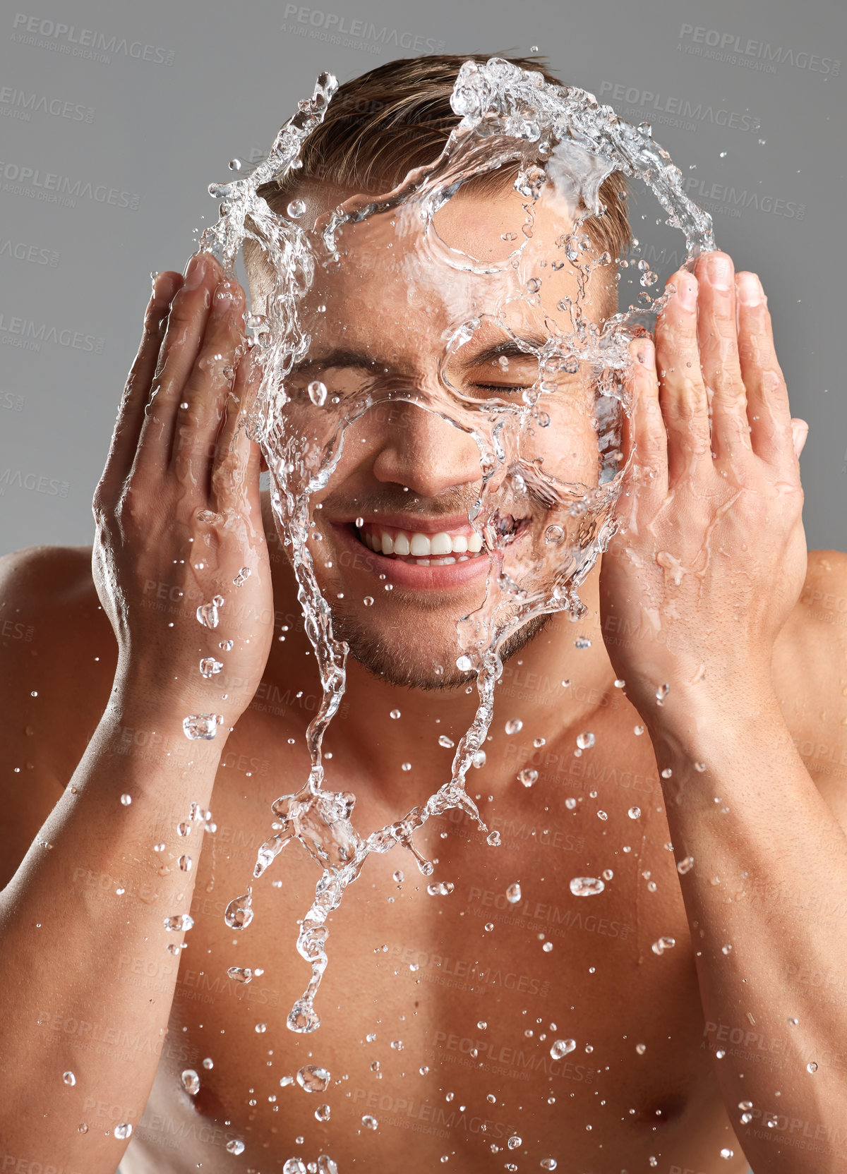 Buy stock photo Studio shot of a handsome young man washing his face against a grey background