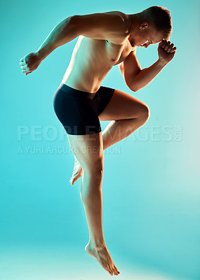 Buy stock photo Studio shot of a handsome young man jumping against a blue background