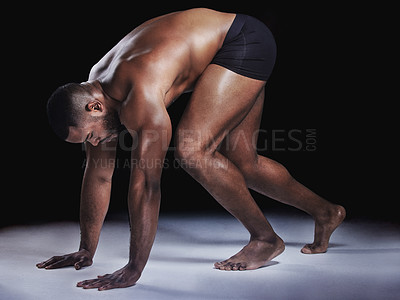 Buy stock photo Studio shot of a young fit man stretching against a black background