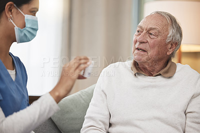 Buy stock photo Shot of a young female nurse helping a patient with their medication during a checkup at home
