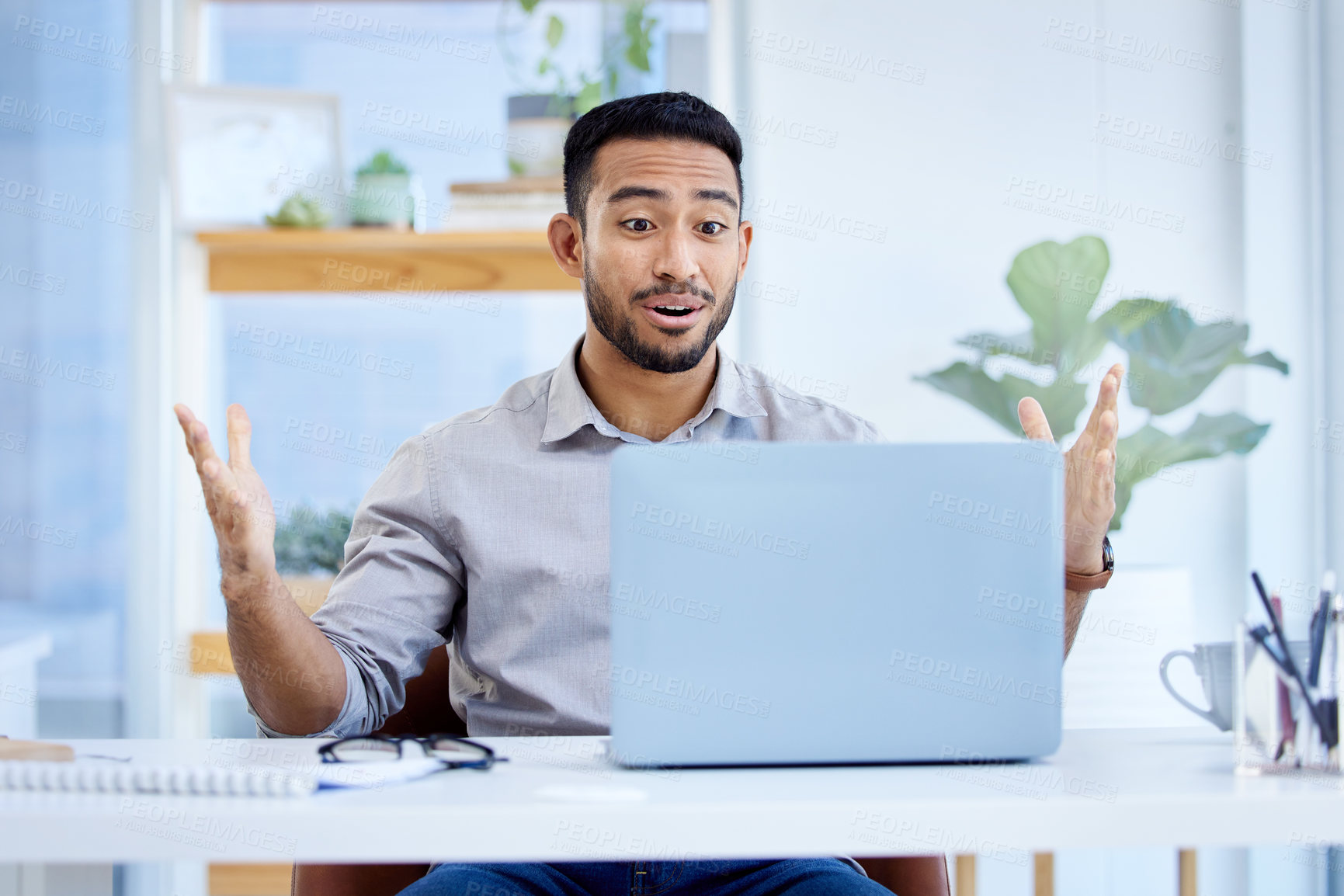 Buy stock photo Shot of a young businessman looking surprised while working on a laptop in an office