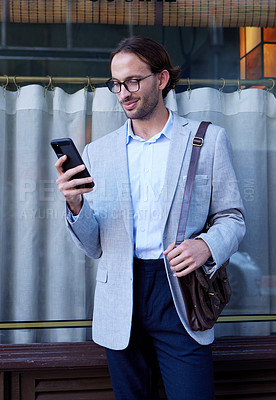 Buy stock photo Shot of a young businessman using a cellphone while out in the city