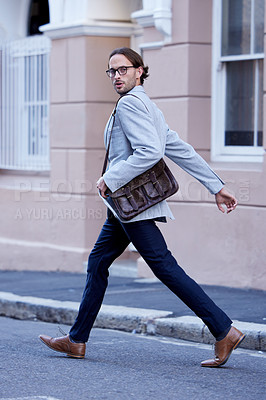 Buy stock photo Portrait of a young businessman walking across a street while out in the city