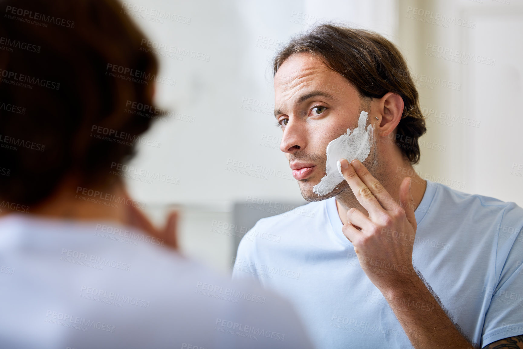 Buy stock photo Shot of a young man applying shaving foam to his face