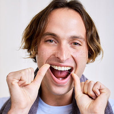 Buy stock photo Shot of a young man flossing his teeth