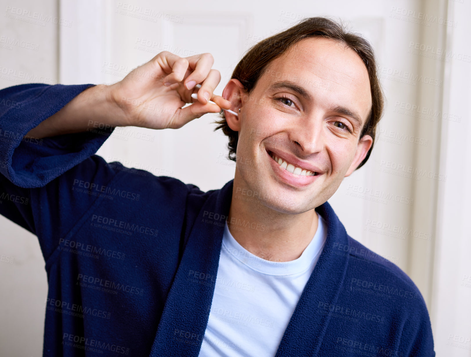 Buy stock photo Shot of a young man using an earbud to clean his ear