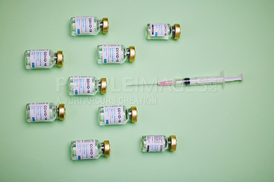 Buy stock photo Shot of vaccines and a syringe against a green background