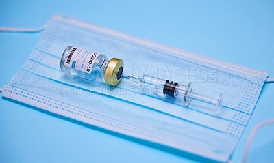 Buy stock photo Studio shot of a vaccine and mask against a blue background