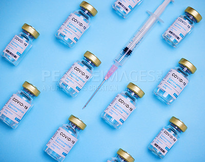 Buy stock photo Shot of vaccines and a syringe against a blue background