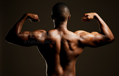 Buy stock photo Rearview studio shot of a fit young man flexing against a black background