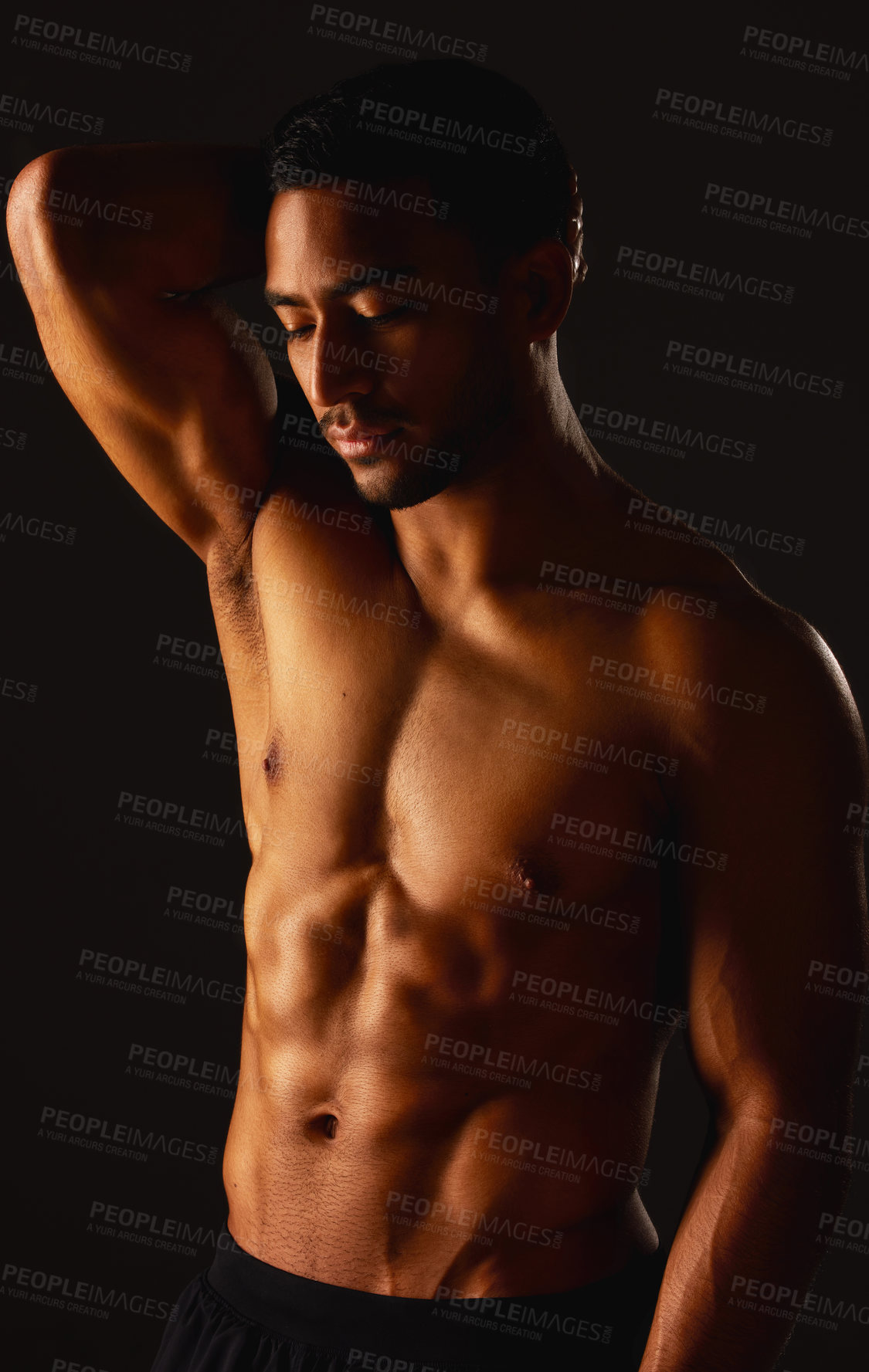 Buy stock photo Studio shot of a fit young man posing against a black background