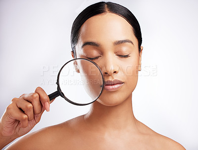 Buy stock photo Studio shot of a beautiful young woman holding a magnifying glass to her face against a white background