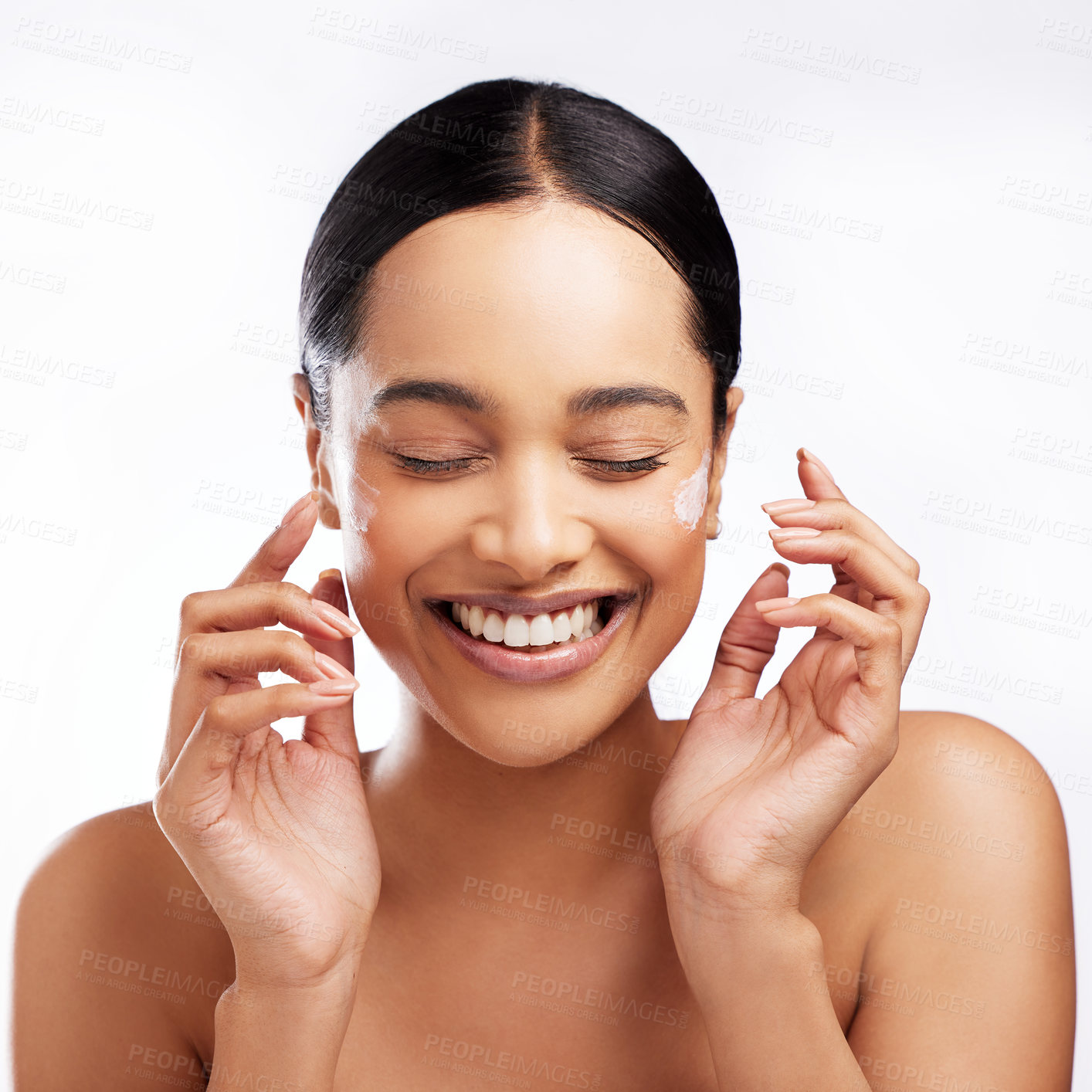 Buy stock photo Studio shot of a beautiful young woman applying moisturiser to her face against a white background