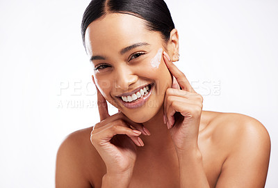 Buy stock photo Studio portrait of a beautiful young woman applying moisturiser to her face against a white background