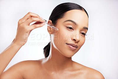 Buy stock photo Studio shot of a beautiful young woman using a serum on her face against a white background