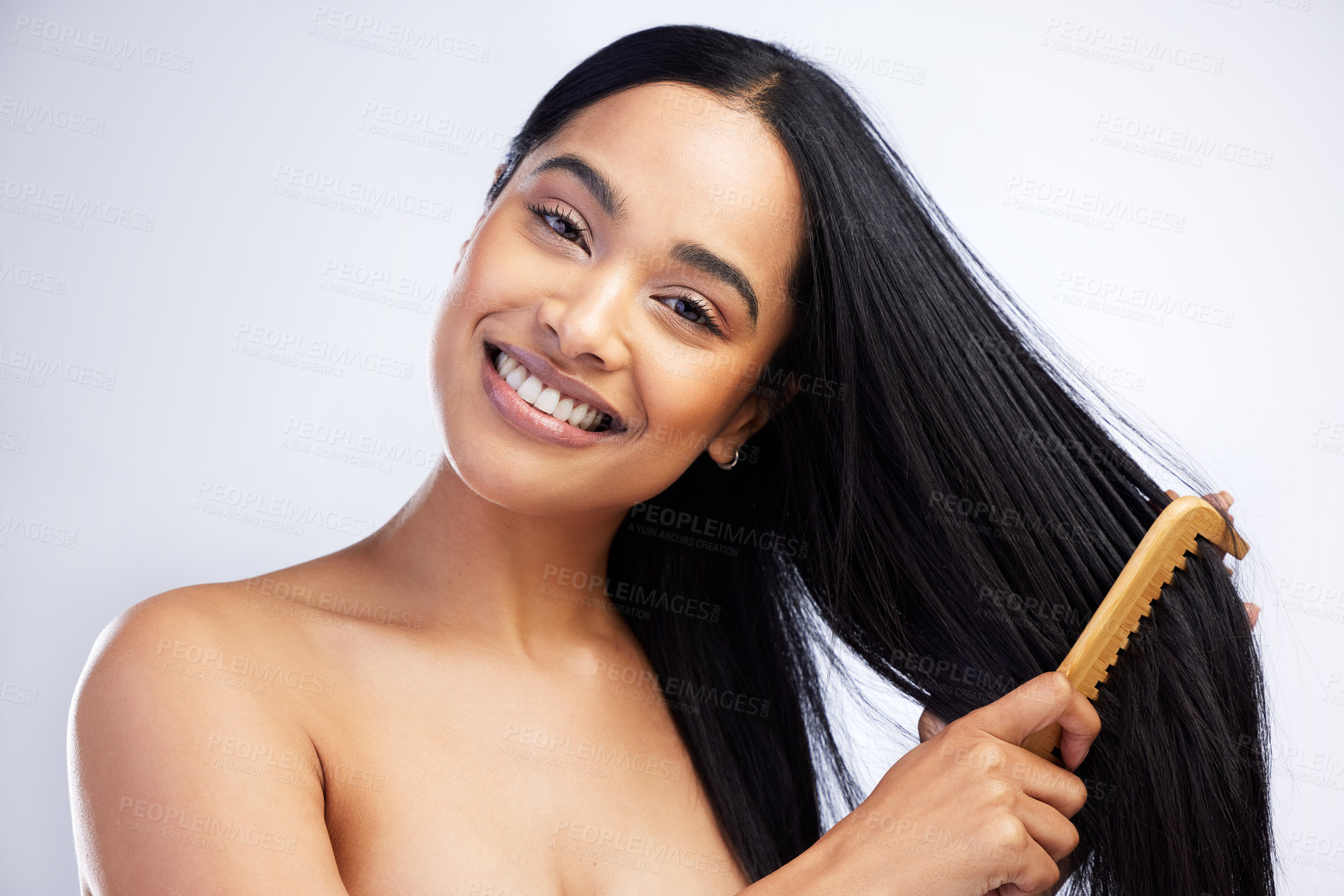 Buy stock photo Shot of an attractive young woman standing alone in the studio and brushing her hair