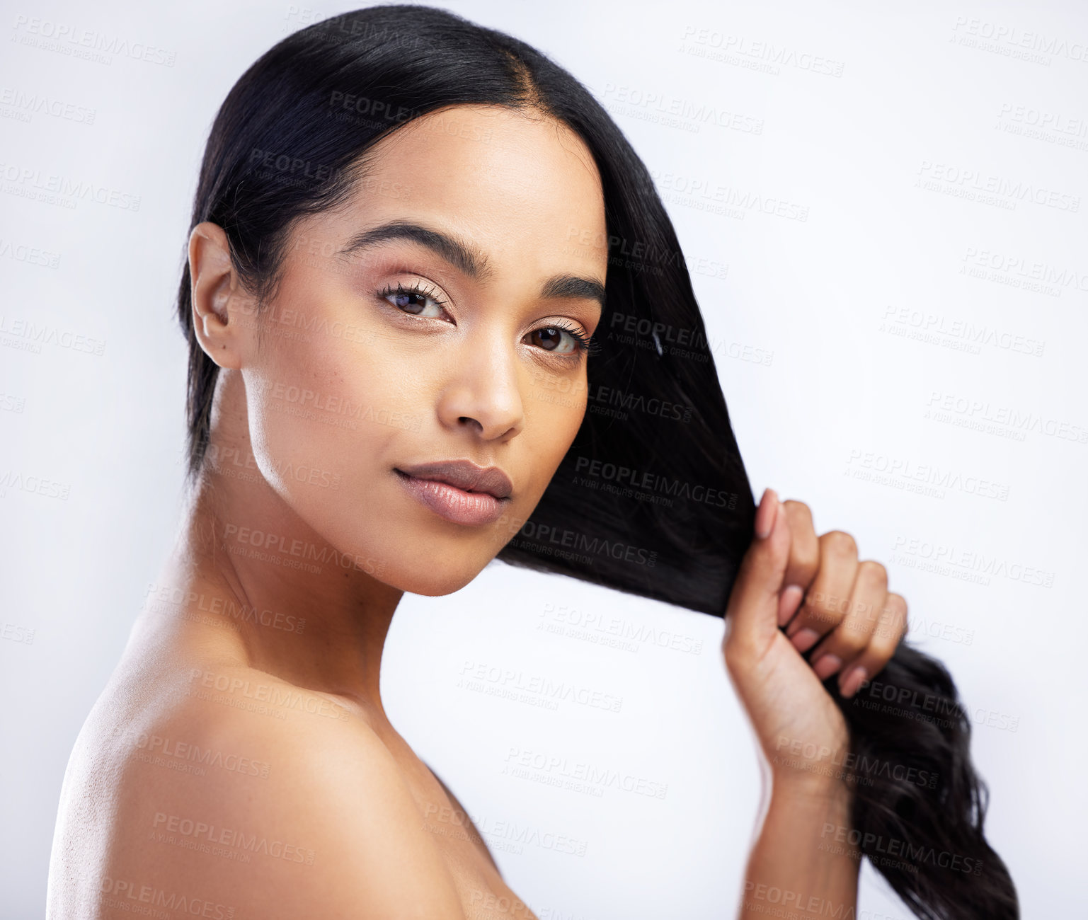 Buy stock photo Shot of an attractive young woman standing alone in the studio and holding her hair