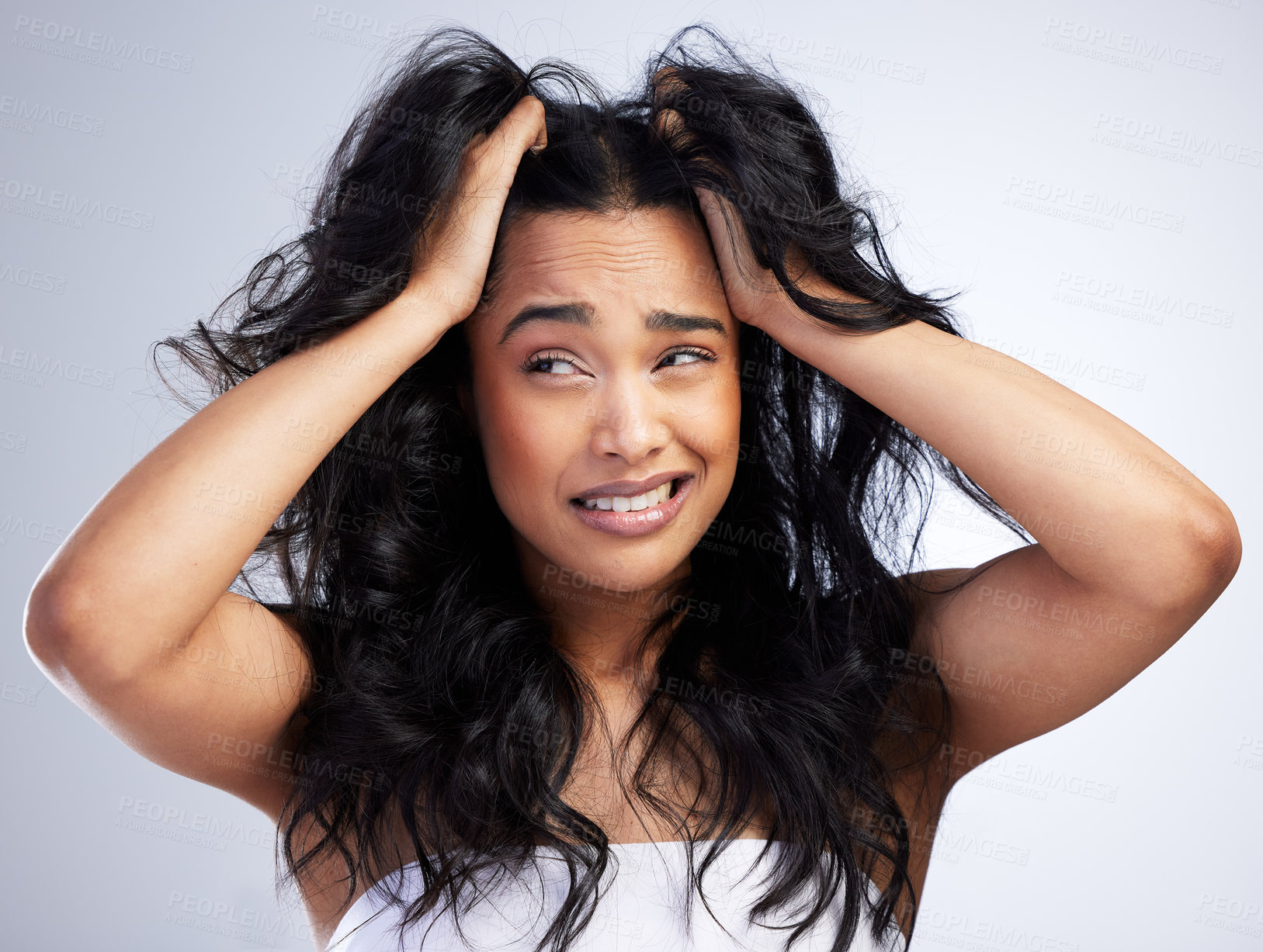 Buy stock photo Shot of an attractive young woman standing alone in the studio and feeling stressed while posing with messy hair