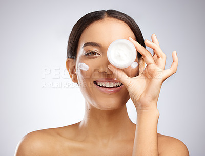 Buy stock photo Studio shot of an attractive young woman holding a tub of moisturiser against a grey background