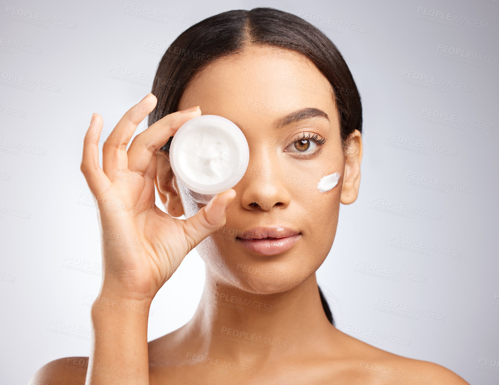 Buy stock photo Studio shot of an attractive young woman holding a tub of moisturiser against a grey background