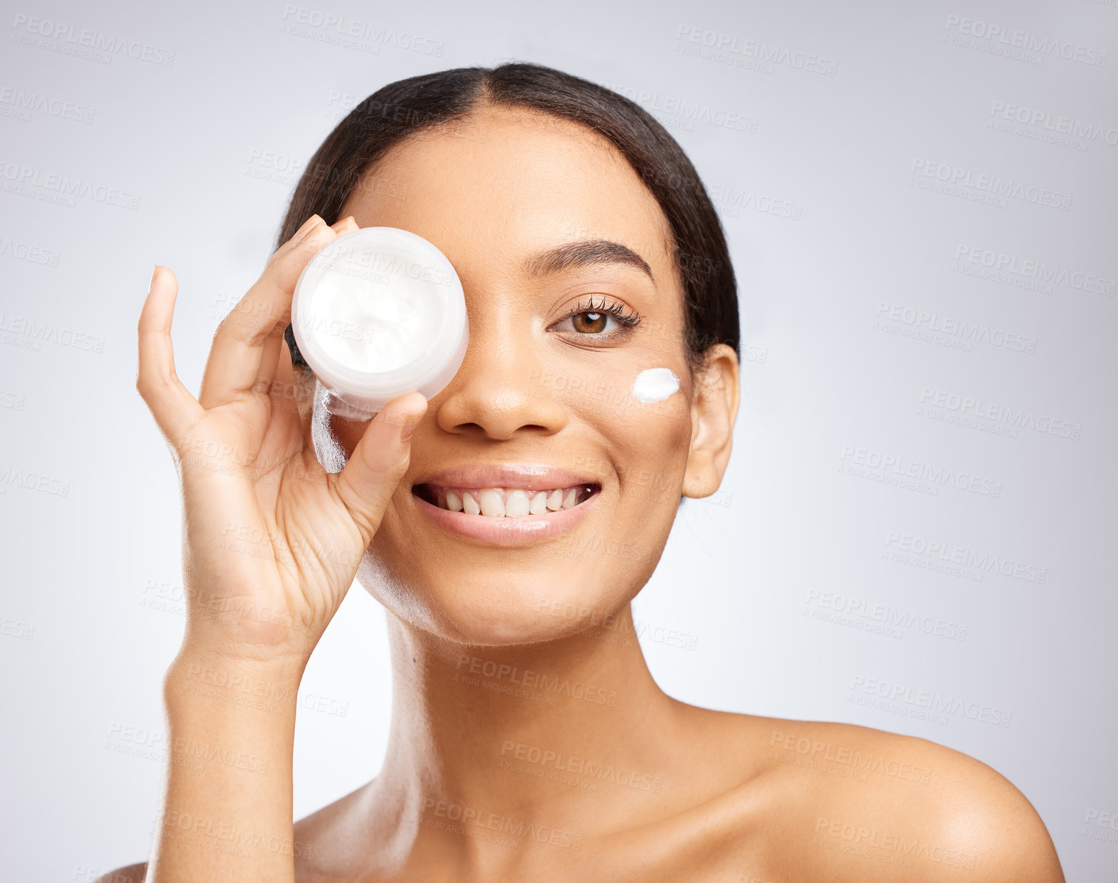 Buy stock photo Studio shot of an attractive young woman holding a tub of moisturiser against a grey background