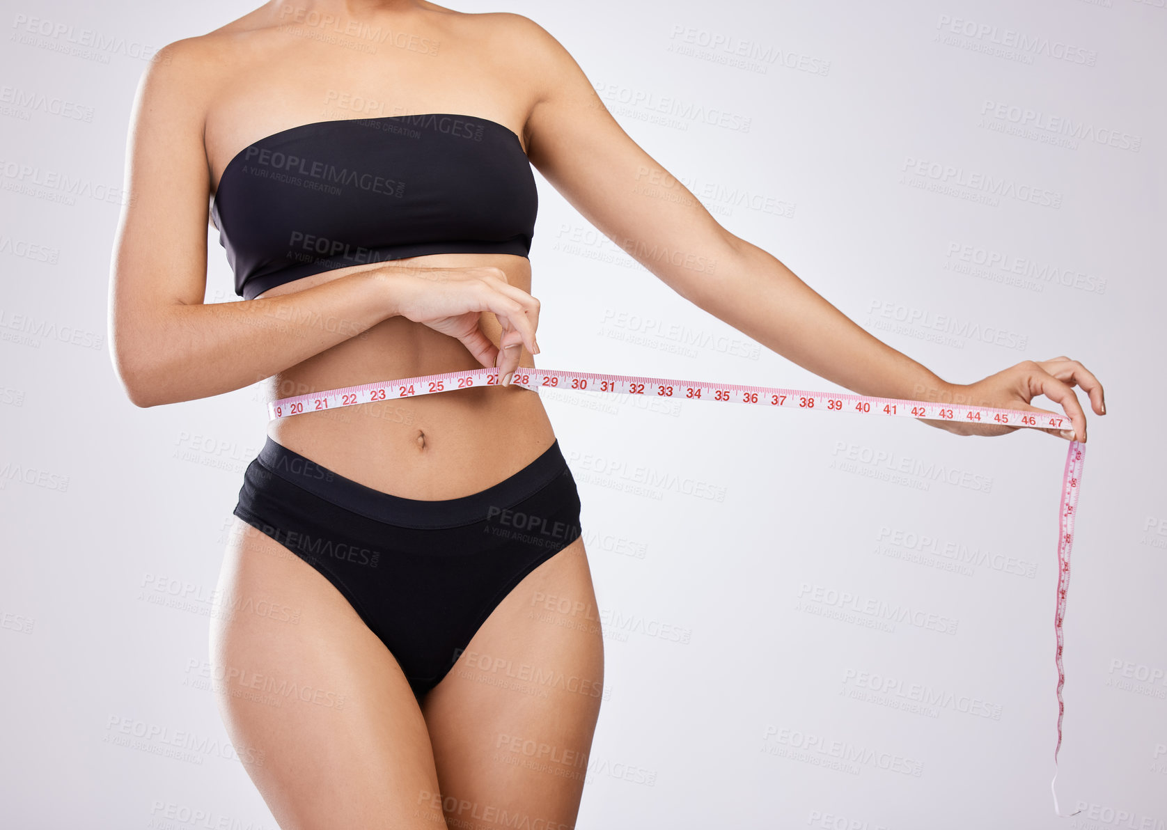 Buy stock photo Studio shot of an unrecognisable woman measuring her waist against a white background