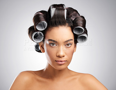 Buy stock photo Studio portrait of an attractive young woman posing with curlers in her hair against a grey background