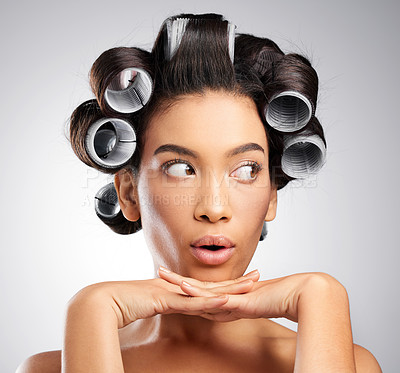 Buy stock photo Studio shot of an attractive young woman posing with curlers in her hair against a grey background
